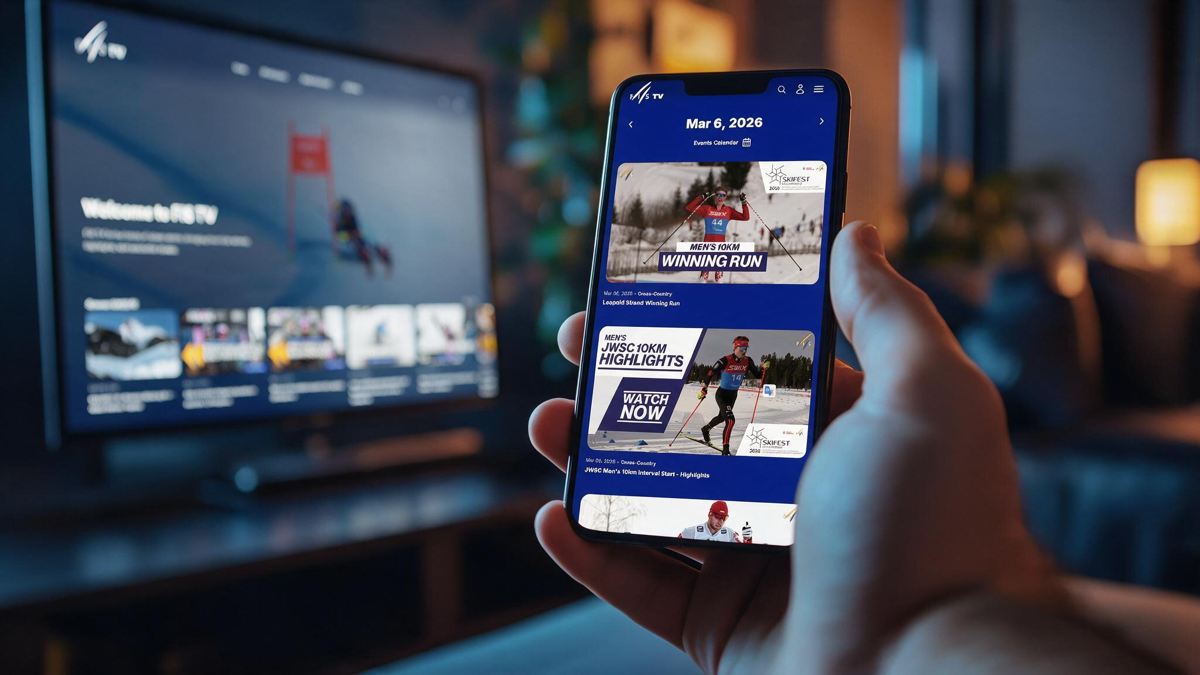 A hand holding a phone showing the FIS TV event calendar, with the FIS TV homepage playing on a television in the background